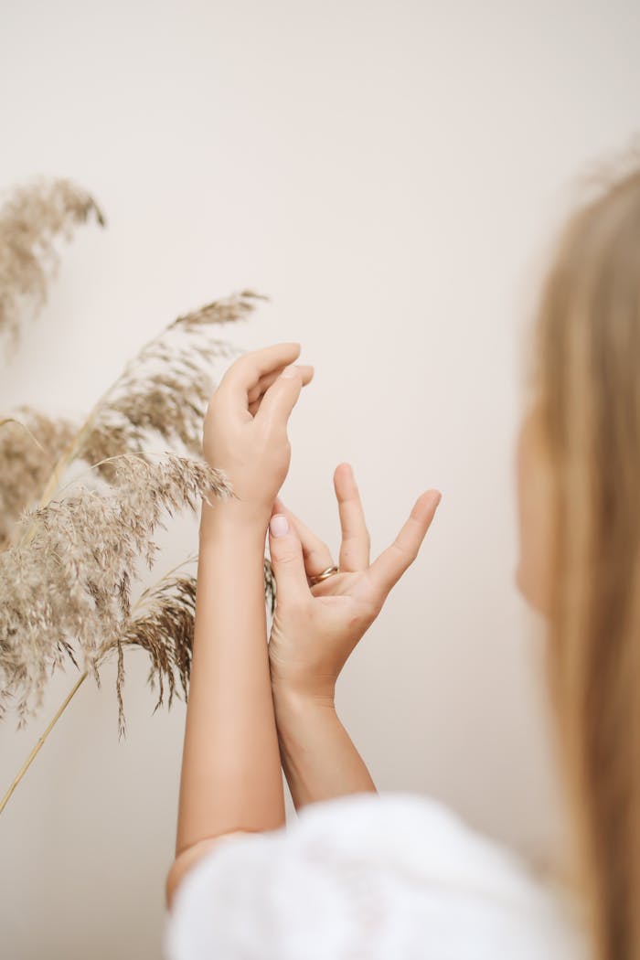 Soft focus on a woman's hands in a minimalist style next to dried grass.